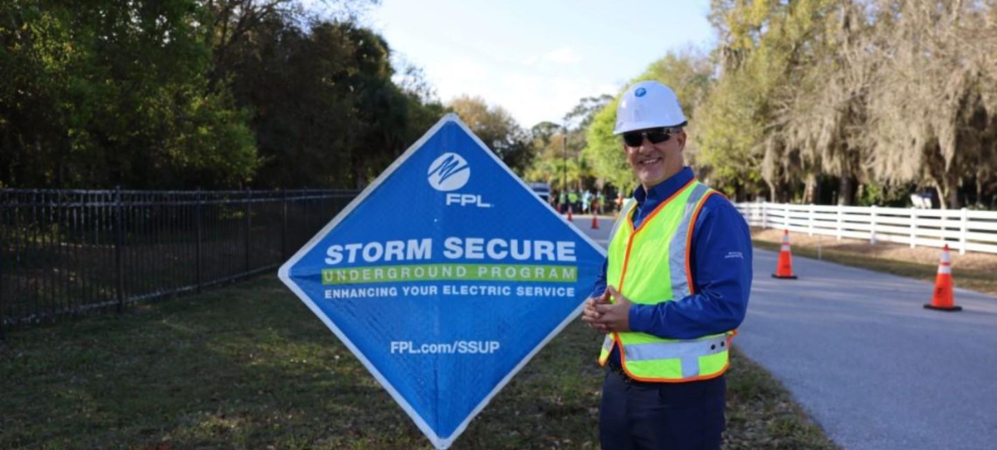 Man in hardhat in front of sign 