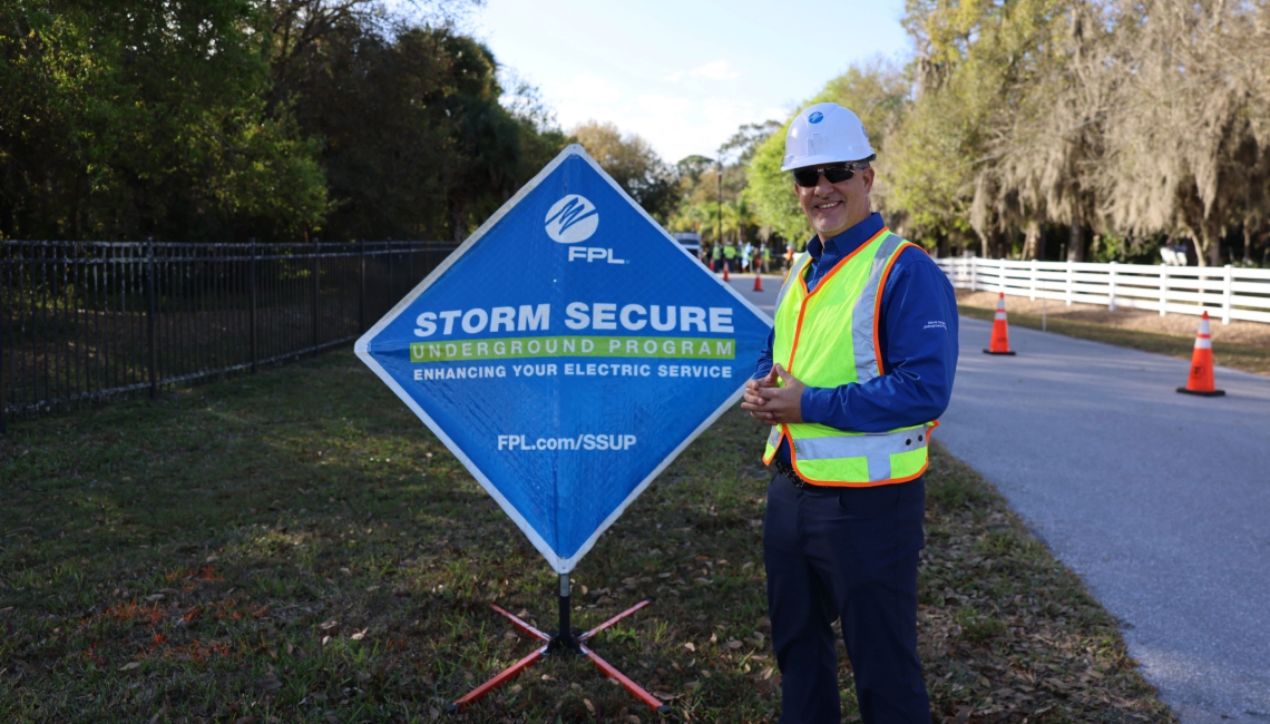 Man in hardhat in front of sign 