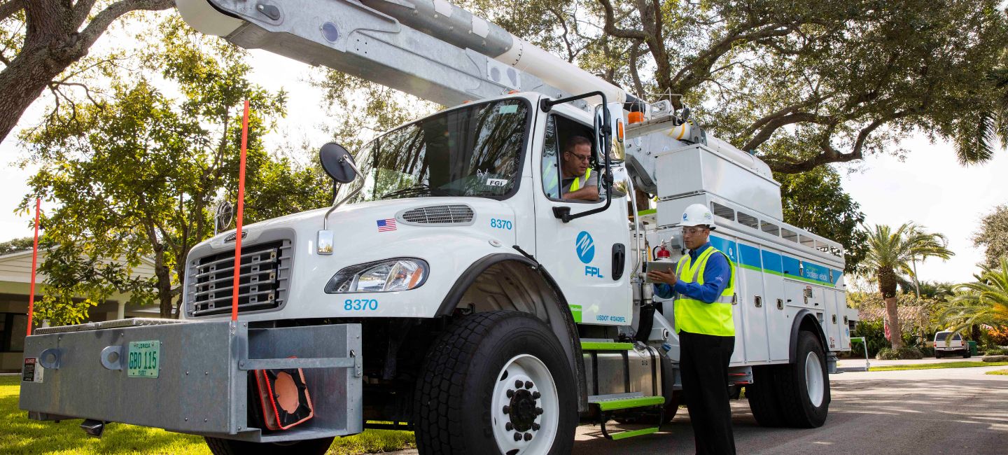 Man in bucket truck talks to man with hard hat