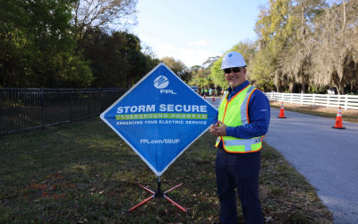 Man in hardhat in front of sign 